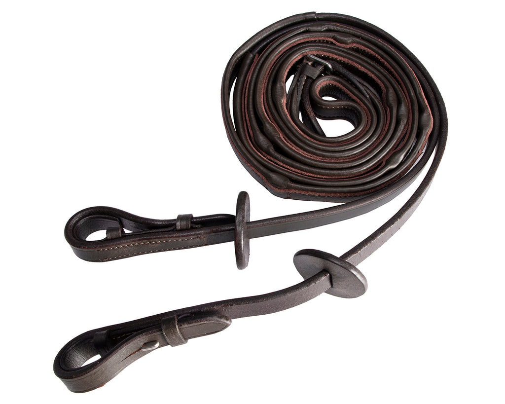 A pair of brown leather reins from Jeremy & Lord with leather-covered stops. The reins are made of soft nappa leather and have a smooth finish. They are being held by a hand, with the grip stops visible. These reins are useful for training and maintaining an even rein length while riding.